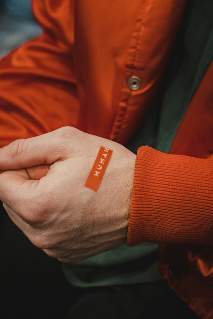 Hand with sticker pasted on it that reads "HUMAN"