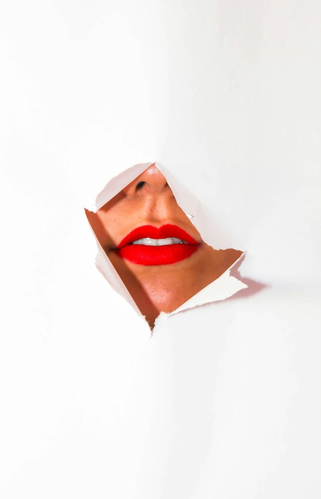 Female mouth behind torn paper